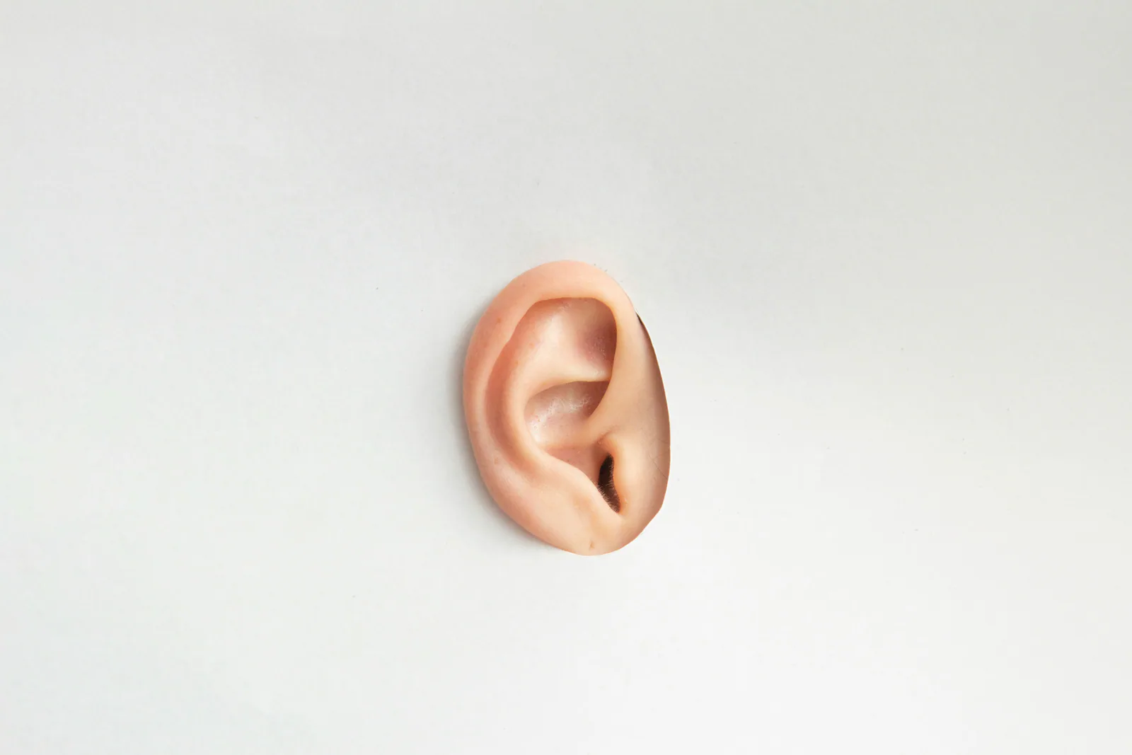 Close-up of an ear on a white wall, representing listening and push-back dynamics in global meetings.