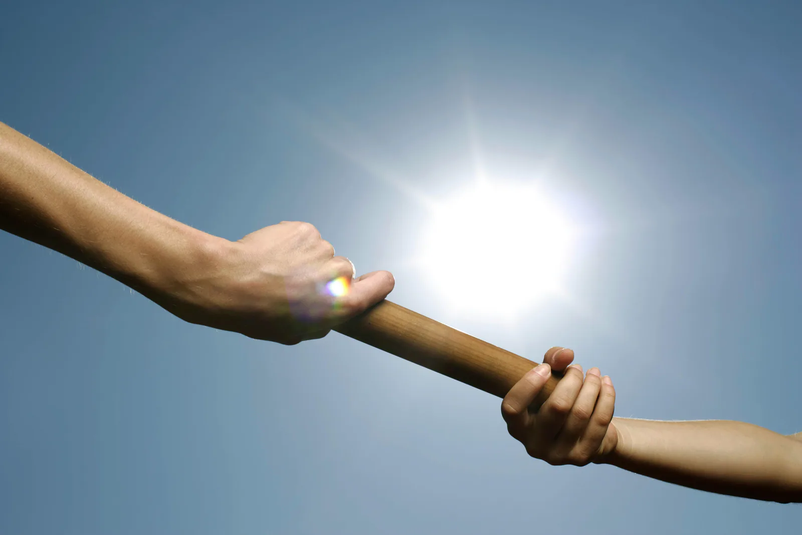 Relay baton handoff, representing cross-border team speed and execution handoffs.