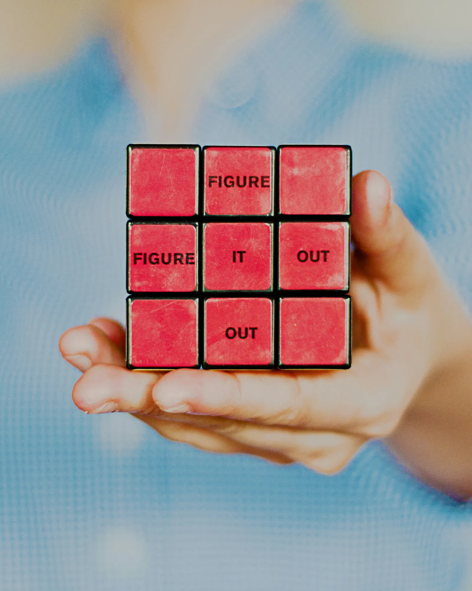 Red cube held in two hands, representing capability blocks and measurable progress.