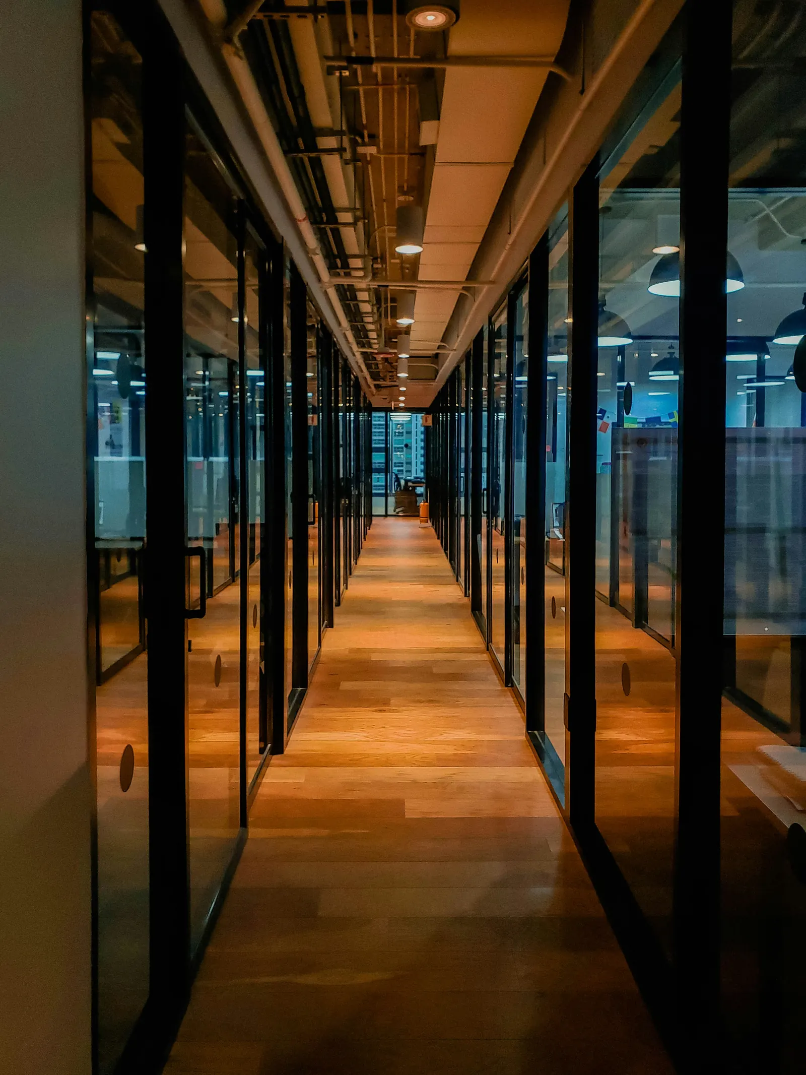 Warm office corridor with glass walls, representing cross-border handoffs and operating passage.