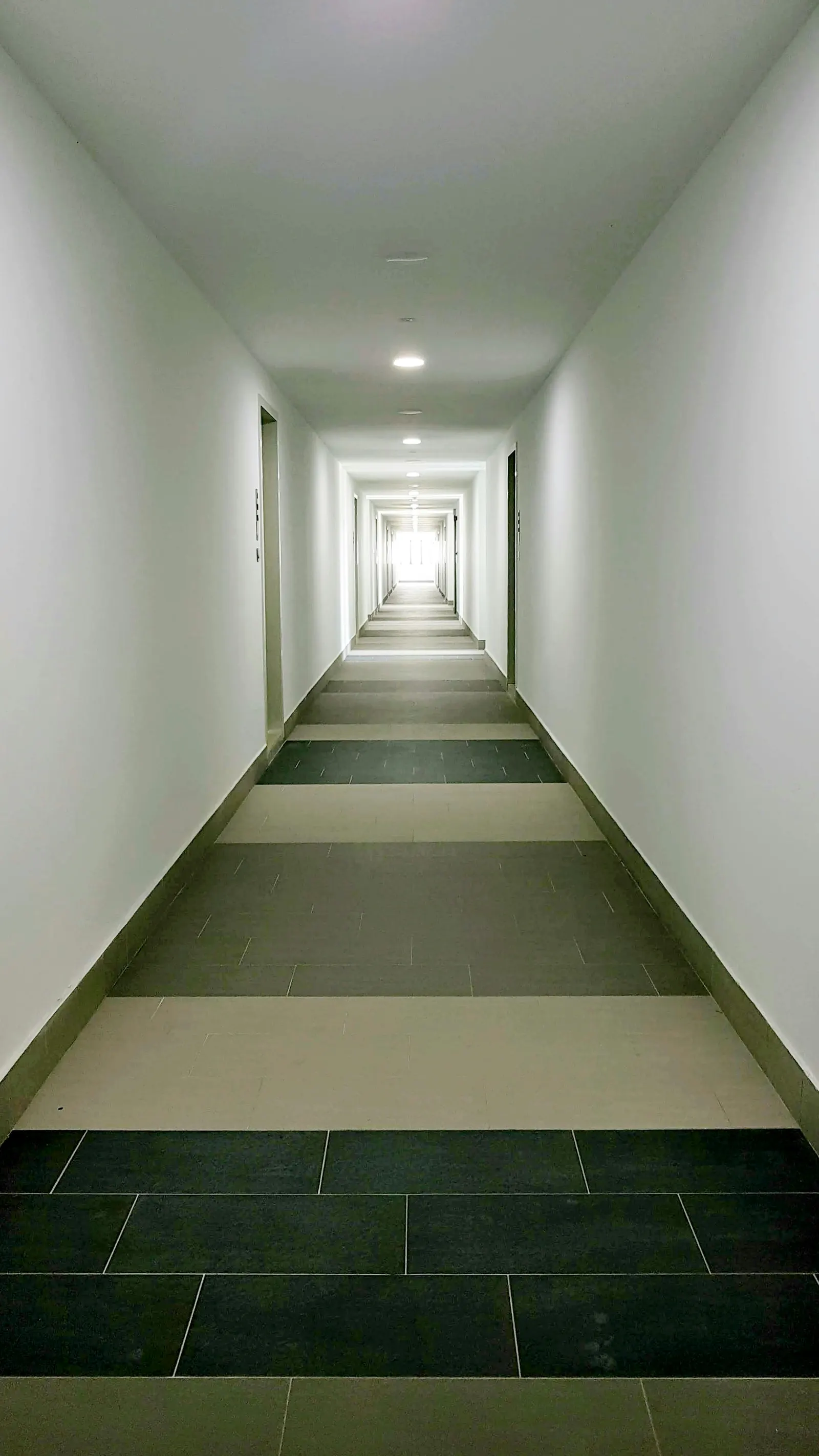 Minimal corridor stairway leading toward light, representing movement from ambiguity to clarity.