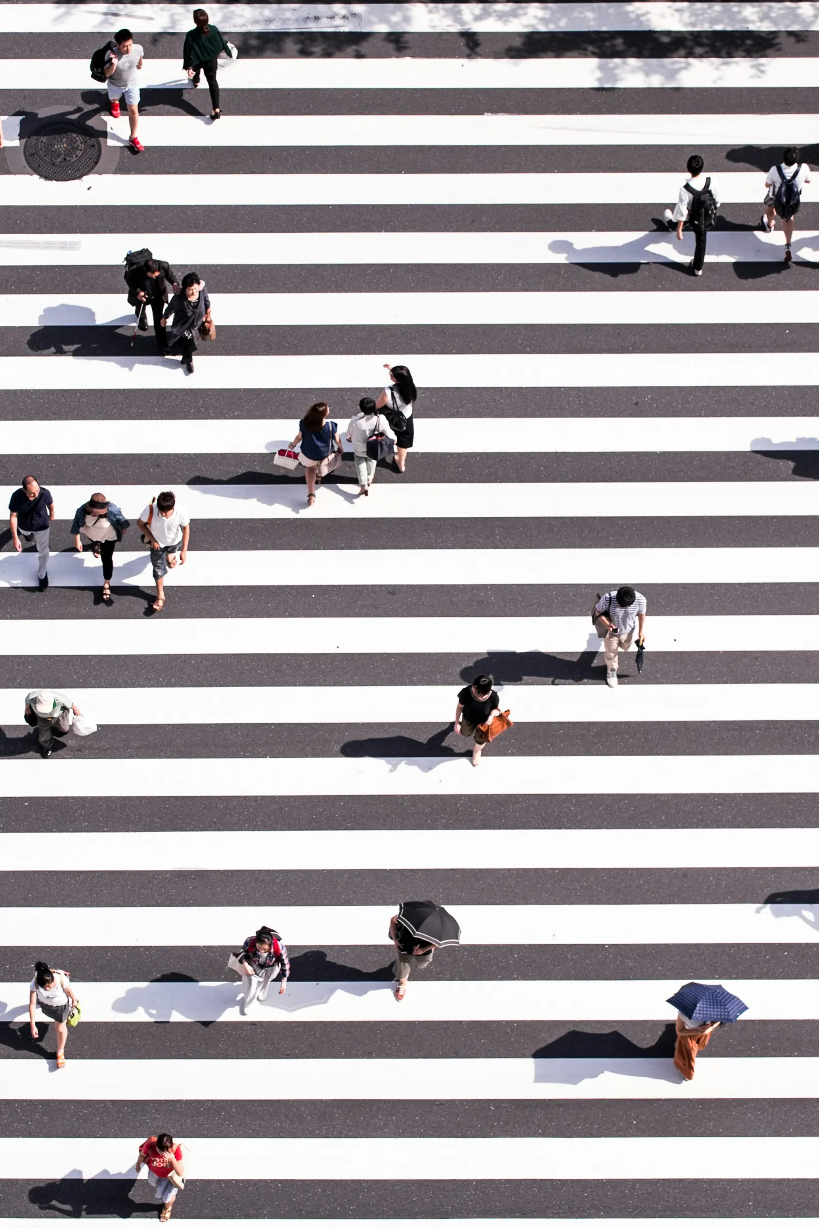 People crossing patterned walkways, representing distributed teams moving through shared systems.