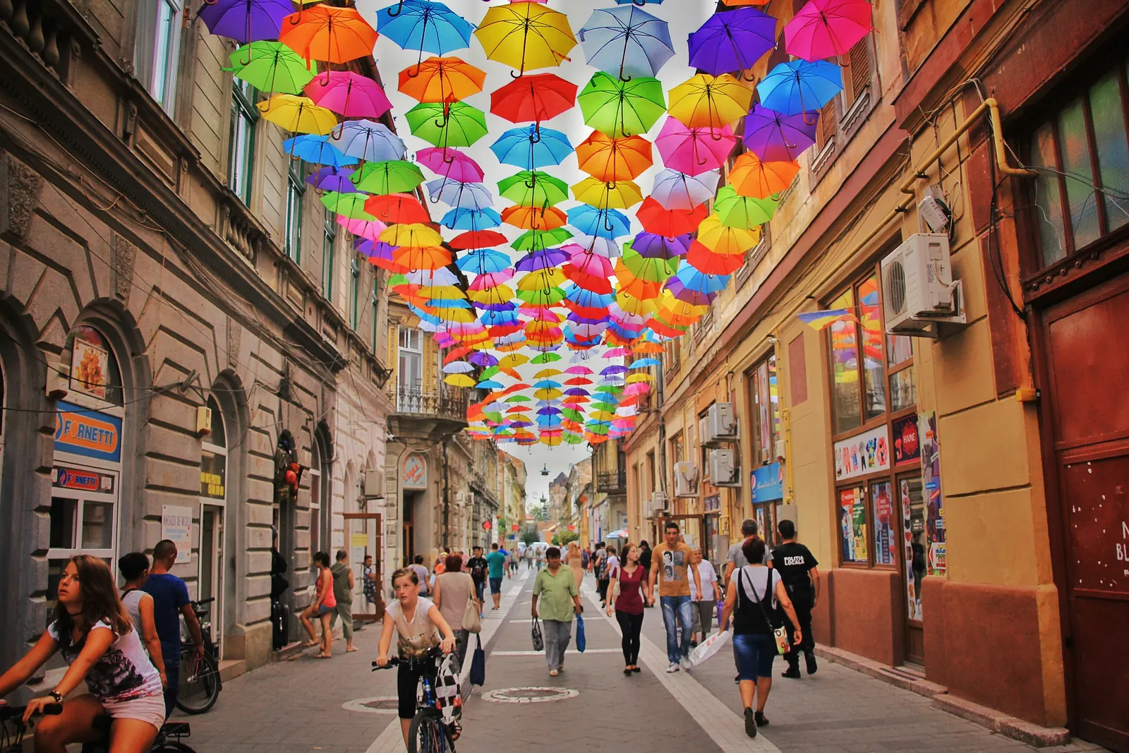 Colorful umbrellas over a city passage, representing visible cultural patterns.