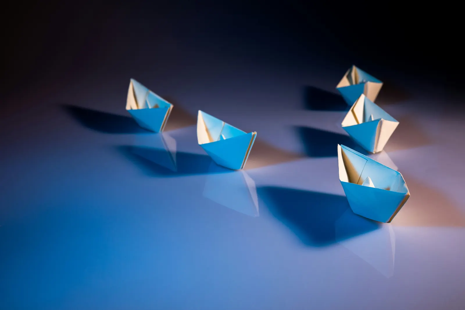 Paper boats arranged in formation, representing leadership direction and team alignment.