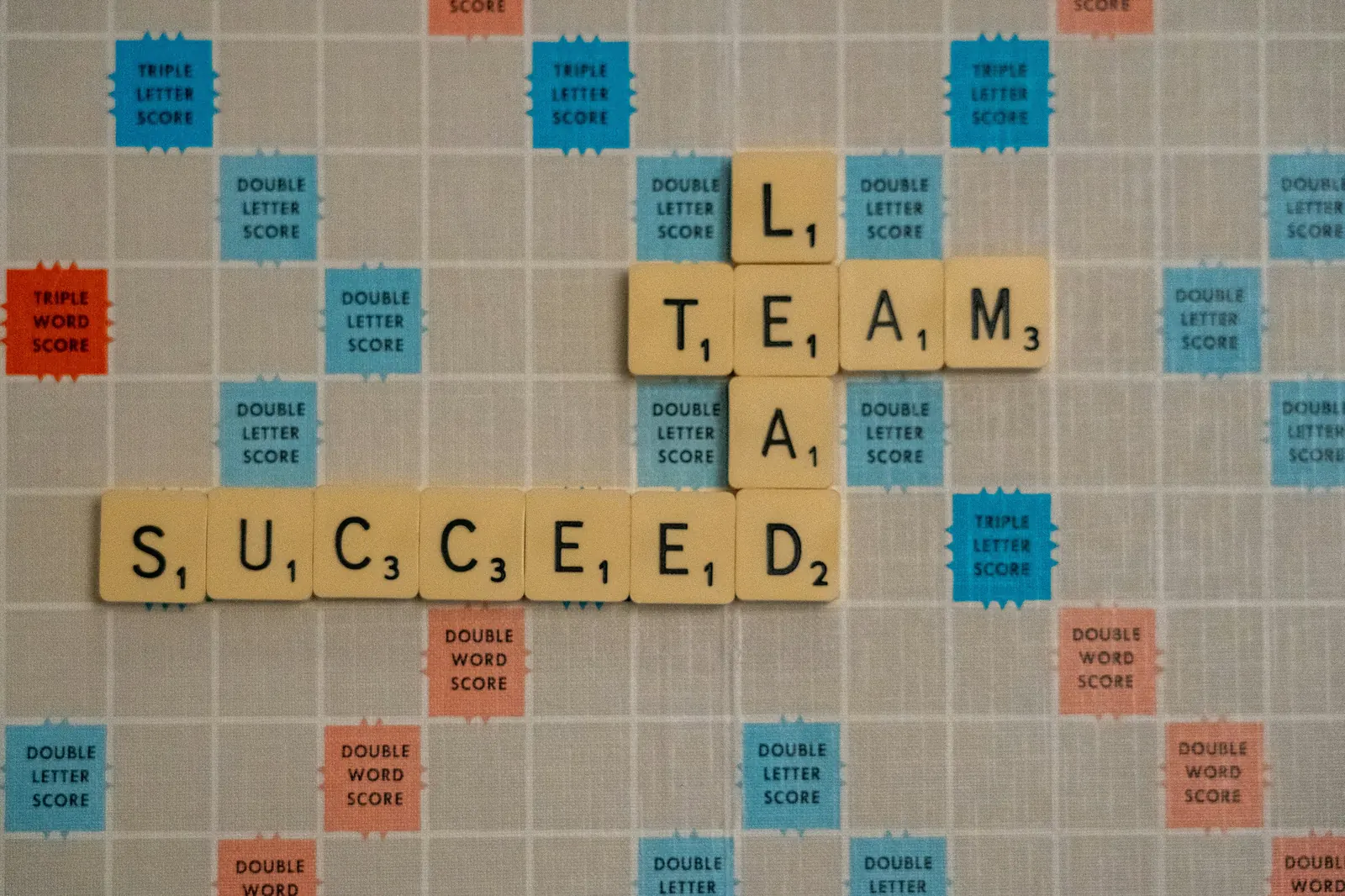 Letter tiles spelling team succeed, representing team performance outcomes.